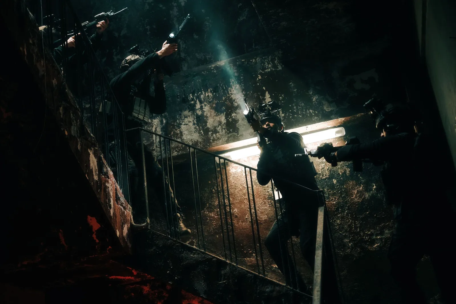 Agentes tácticos con casco y visión nocturna aseguran de noche una escalera oscura.
